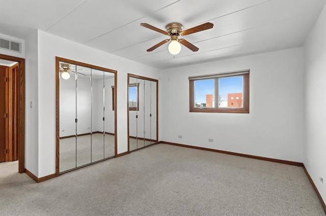 unfurnished bedroom featuring baseboards, visible vents, multiple closets, and carpet flooring