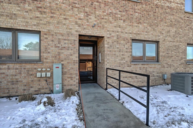 snow covered property entrance featuring central AC