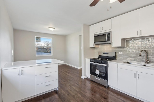 kitchen featuring dark wood finished floors, light countertops, backsplash, appliances with stainless steel finishes, and a sink