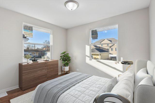 bedroom with multiple windows, wood finished floors, and baseboards