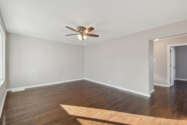 spare room with ceiling fan, visible vents, baseboards, and dark wood-style flooring