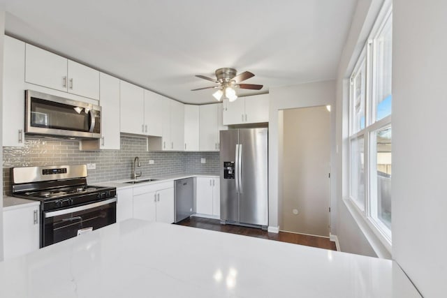 kitchen with tasteful backsplash, light countertops, appliances with stainless steel finishes, white cabinetry, and a sink