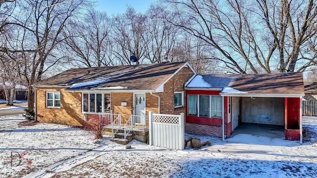 view of front facade featuring fence, a carport, and brick siding