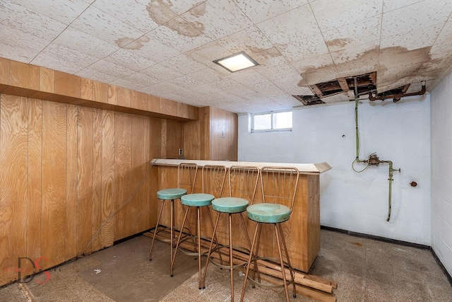 bar featuring concrete flooring, wooden walls, and a bar