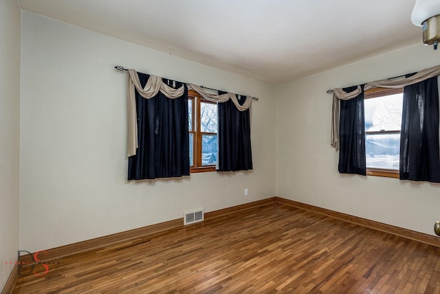 spare room featuring baseboards, visible vents, and hardwood / wood-style floors