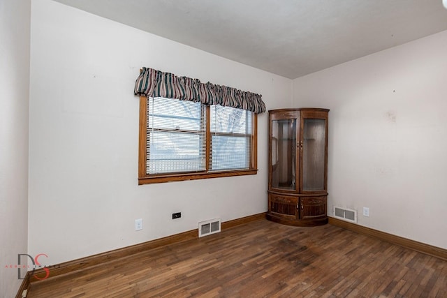 spare room with visible vents, baseboards, and hardwood / wood-style flooring