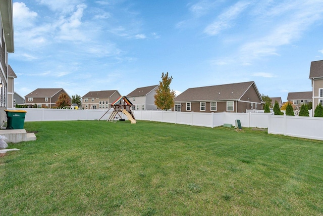 view of yard featuring a playground, a fenced backyard, and a residential view