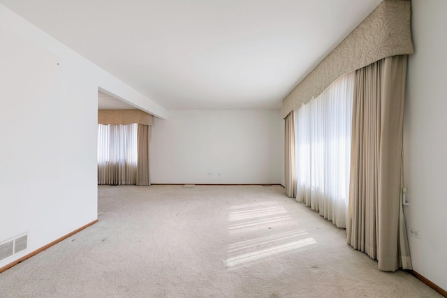 unfurnished room featuring visible vents, light carpet, and baseboards