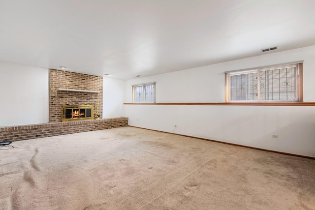 unfurnished living room featuring baseboards, visible vents, a fireplace, and carpet flooring