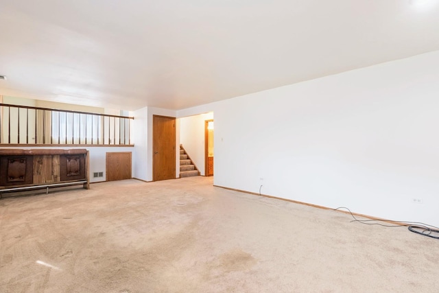 unfurnished living room featuring stairs, carpet floors, and visible vents