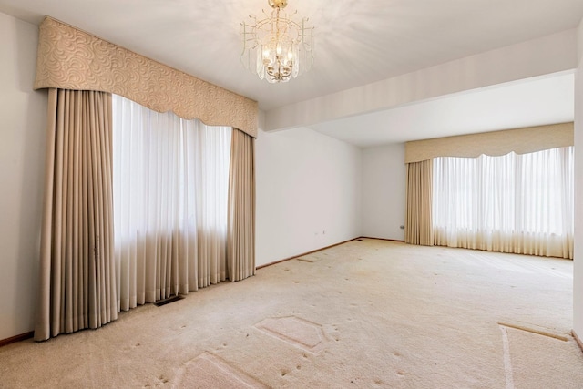 unfurnished room featuring carpet flooring, a notable chandelier, and baseboards