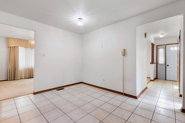 spare room with a wealth of natural light, visible vents, baseboards, and light tile patterned floors