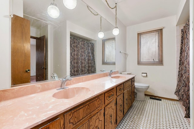 full bath featuring toilet, double vanity, baseboards, and a sink