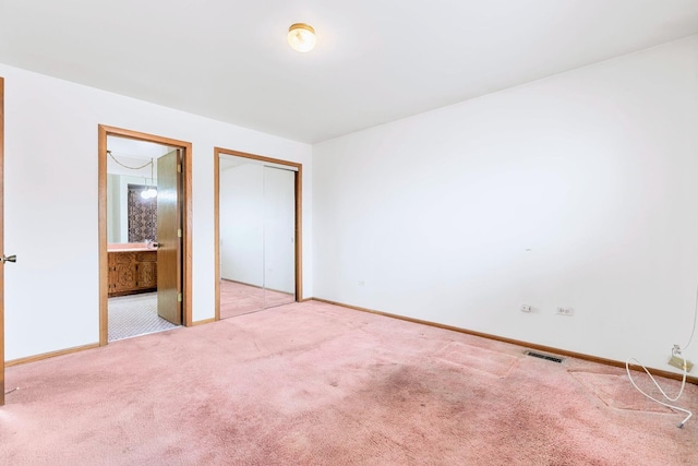 unfurnished bedroom with ensuite bathroom, a closet, carpet, and baseboards