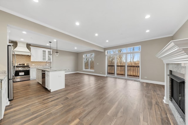 interior space with dark wood-type flooring, a fireplace, a sink, baseboards, and crown molding