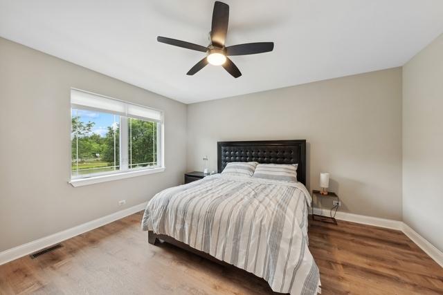 bedroom featuring visible vents, ceiling fan, baseboards, and wood finished floors