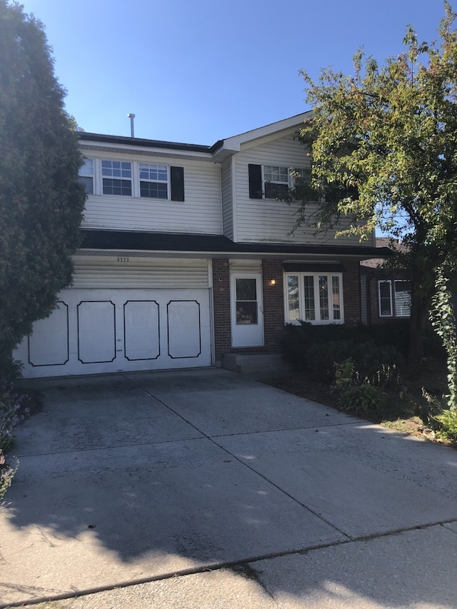 view of front of home featuring a garage, brick siding, and driveway