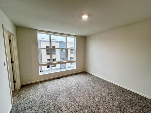 unfurnished room with carpet floors, visible vents, and baseboards