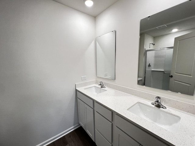 full bathroom featuring a stall shower, a sink, baseboards, and double vanity