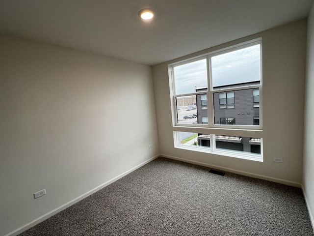 spare room with carpet, visible vents, and baseboards