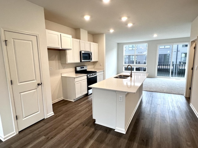 kitchen with stainless steel appliances, a kitchen island with sink, a sink, and white cabinetry