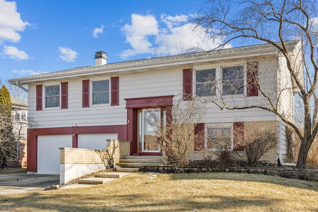 split foyer home with an attached garage, a chimney, concrete driveway, and brick siding