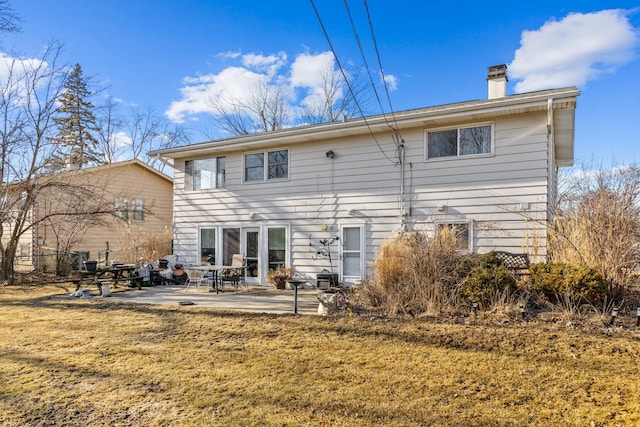 rear view of property featuring a patio area, a yard, and a chimney