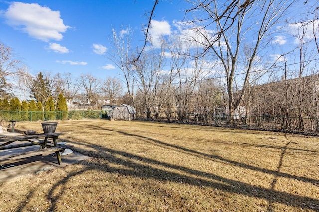 view of yard featuring an outbuilding, fence, and a storage shed