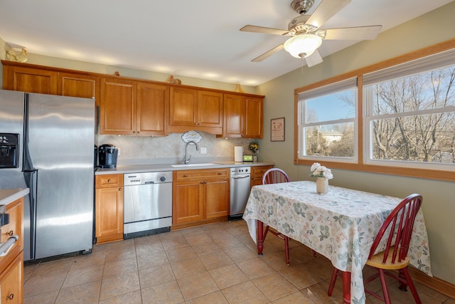 kitchen with a sink, light countertops, appliances with stainless steel finishes, decorative backsplash, and brown cabinetry