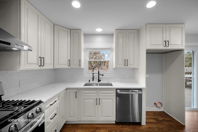 kitchen with a healthy amount of sunlight, wall chimney exhaust hood, stainless steel appliances, and a sink