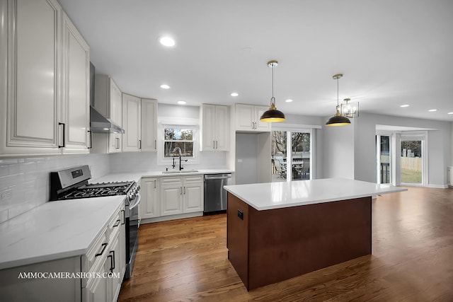 kitchen with wood finished floors, a sink, light countertops, appliances with stainless steel finishes, and backsplash