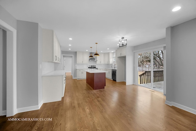 kitchen featuring a kitchen island, light wood-style floors, light countertops, wall chimney range hood, and dishwasher