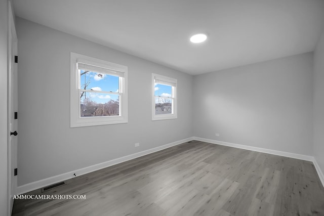 spare room featuring baseboards, visible vents, and wood finished floors