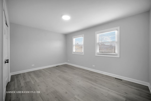 unfurnished room with visible vents, baseboards, and wood finished floors