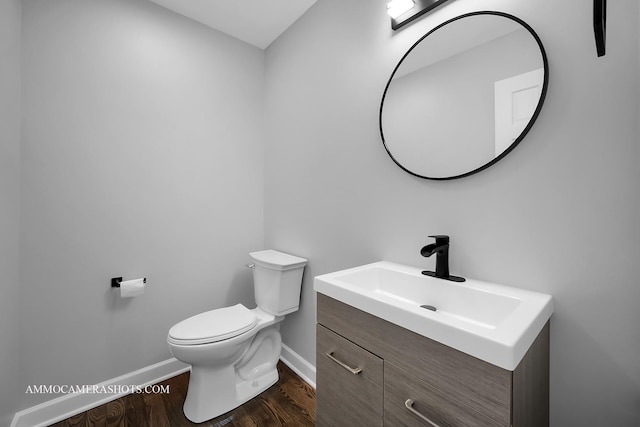 half bathroom featuring baseboards, vanity, toilet, and wood finished floors