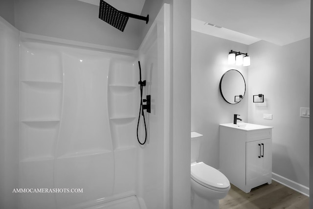 bathroom with visible vents, a shower, toilet, wood finished floors, and vanity