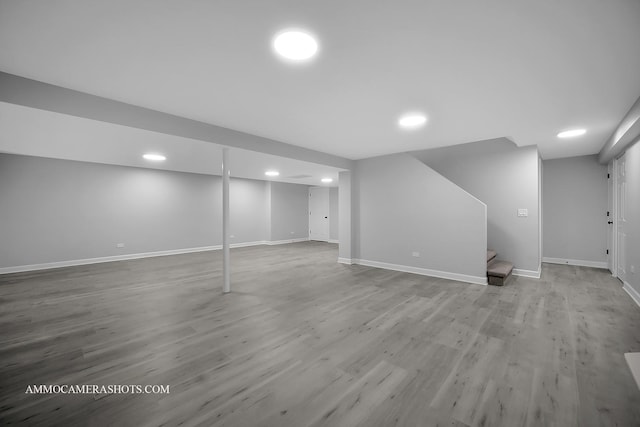 finished below grade area featuring recessed lighting, stairway, baseboards, and wood finished floors