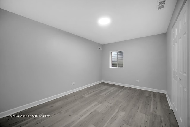 spare room with wood finished floors, visible vents, and baseboards