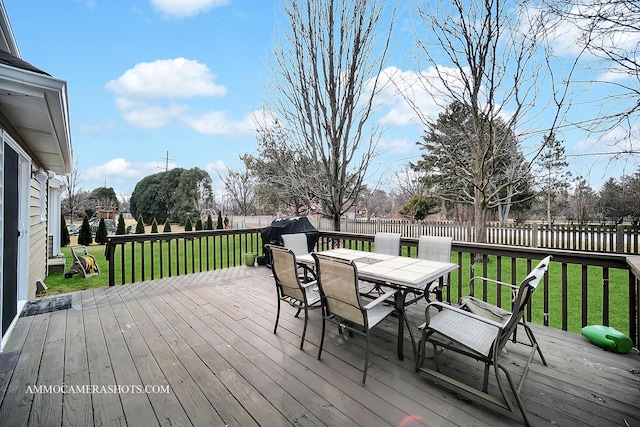 wooden terrace with outdoor dining area, fence, and a lawn