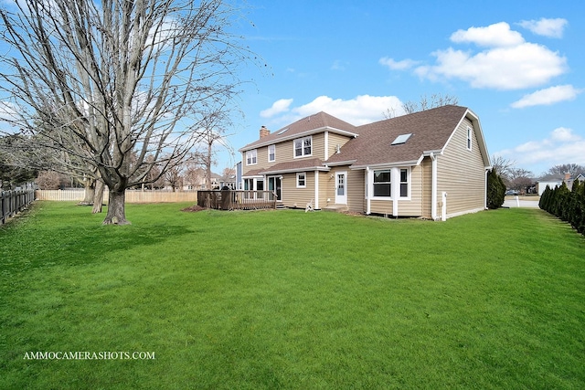 rear view of property featuring a lawn, a chimney, roof with shingles, fence private yard, and a wooden deck