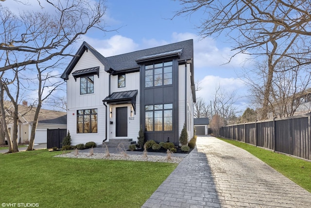 modern inspired farmhouse featuring a shingled roof, fence, board and batten siding, a standing seam roof, and a front yard