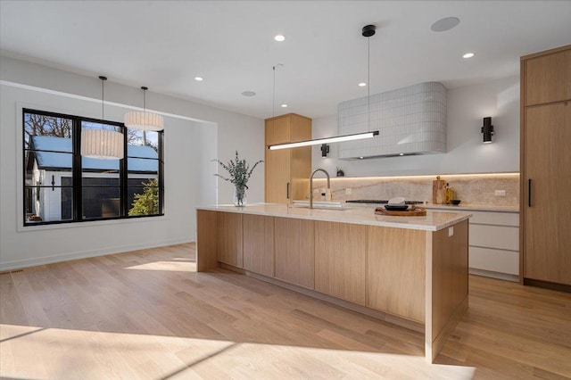 kitchen with light wood finished floors, tasteful backsplash, light countertops, a sink, and modern cabinets