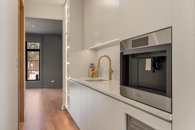 kitchen featuring tasteful backsplash, white cabinets, a sink, and modern cabinets