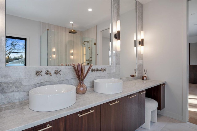 full bathroom featuring double vanity, decorative backsplash, walk in shower, and a sink