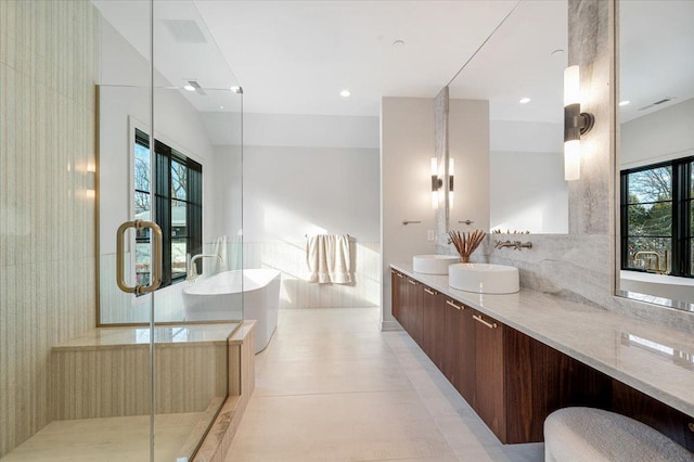 bathroom featuring a sink, a freestanding bath, vaulted ceiling, double vanity, and a stall shower