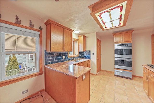 kitchen with a warming drawer, tasteful backsplash, double oven, a sink, and a peninsula