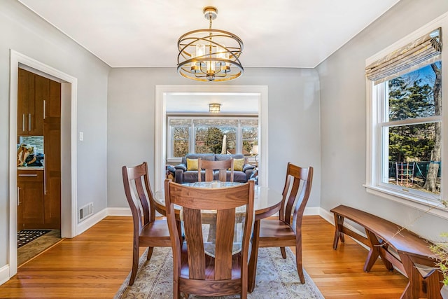 dining room featuring light wood-type flooring, visible vents, baseboards, and a notable chandelier