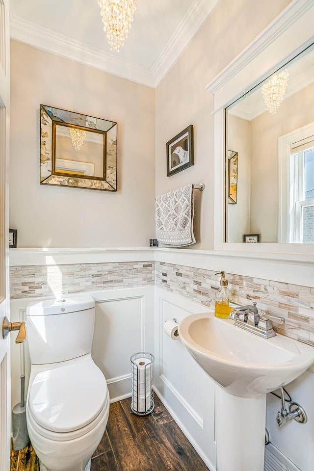 bathroom with toilet, a notable chandelier, wood finished floors, and ornamental molding