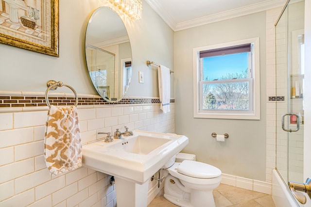 bathroom with toilet, tile walls, crown molding, tile patterned flooring, and baseboards