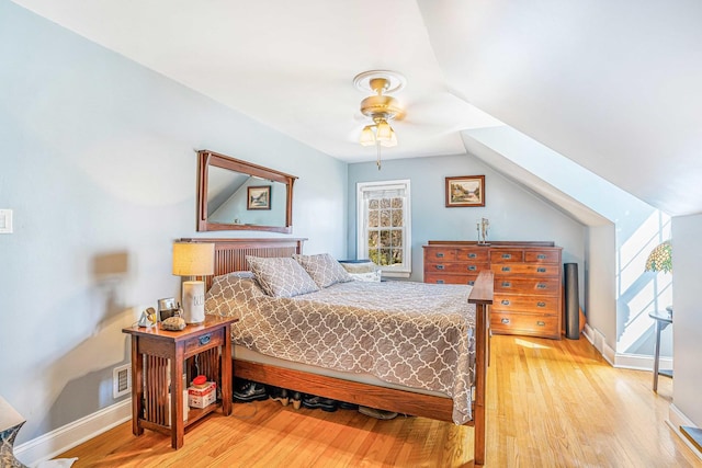 bedroom with baseboards, multiple windows, wood finished floors, and vaulted ceiling